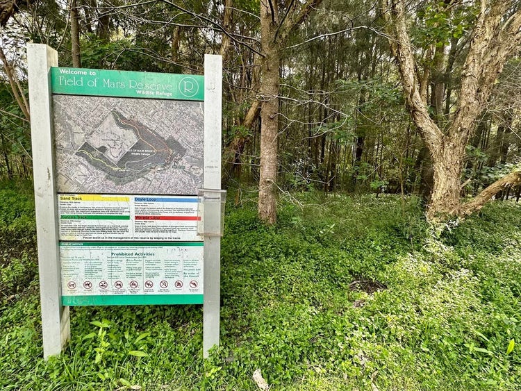Ground covers, paper bark tea trees and Field of Mars Reserve visitor map and sign.
