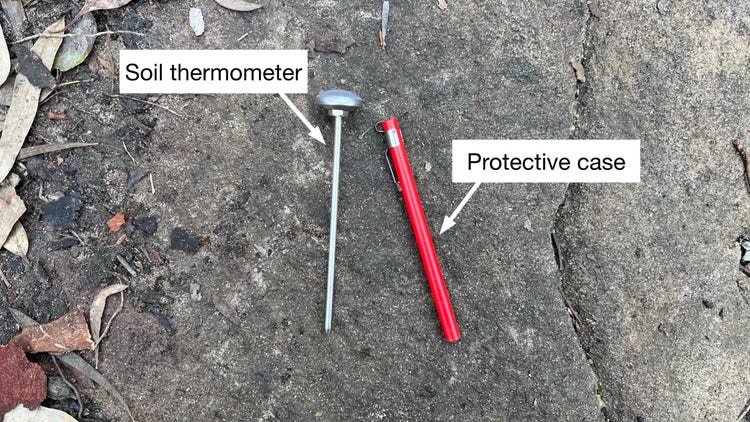 Soil thermometer lying on a rock with a label showing the protective case